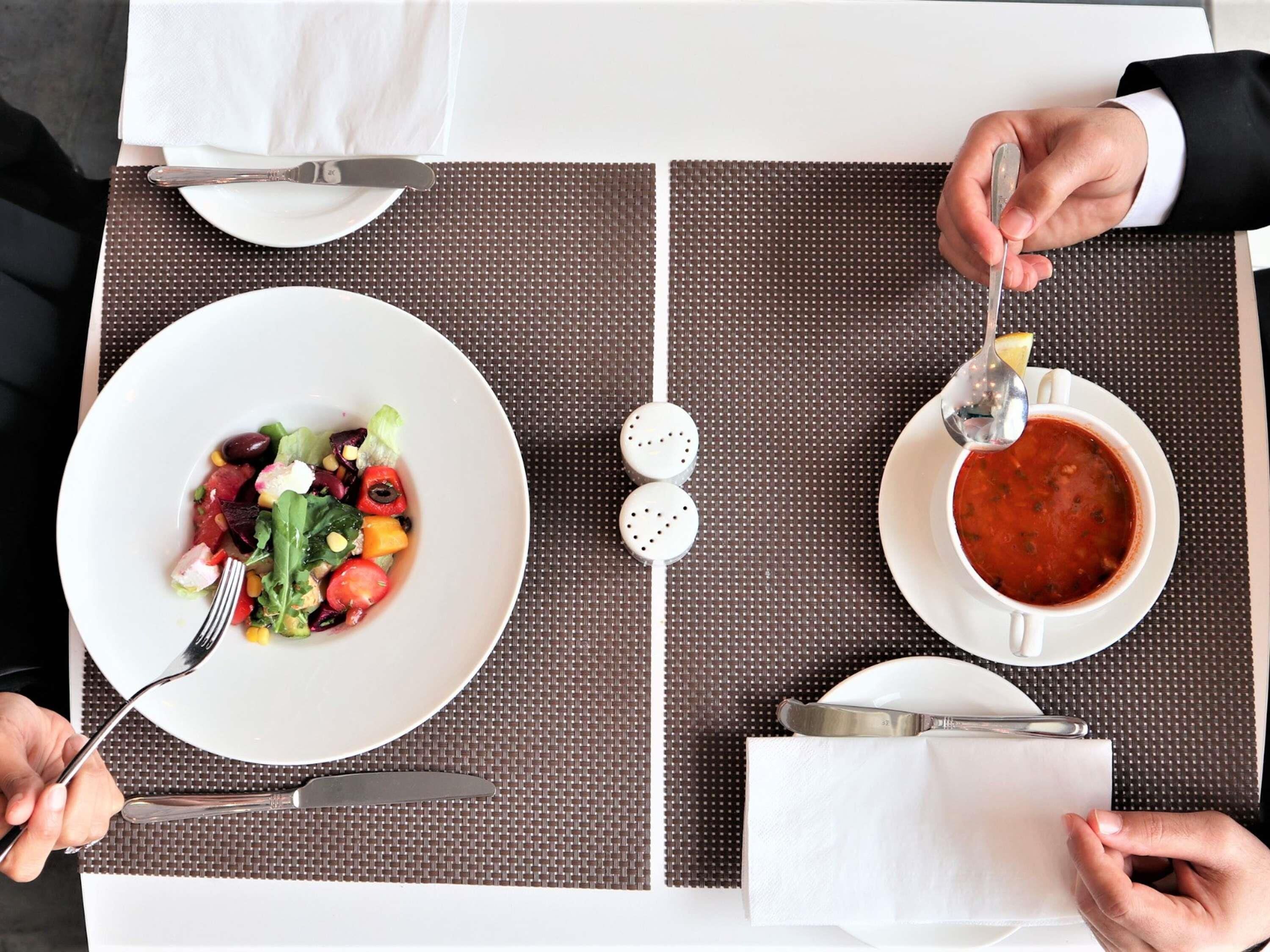 Ein Esstisch mit Salat und Suppe, Salz- und Pfefferstreuern sowie einem Serviettenhalter.