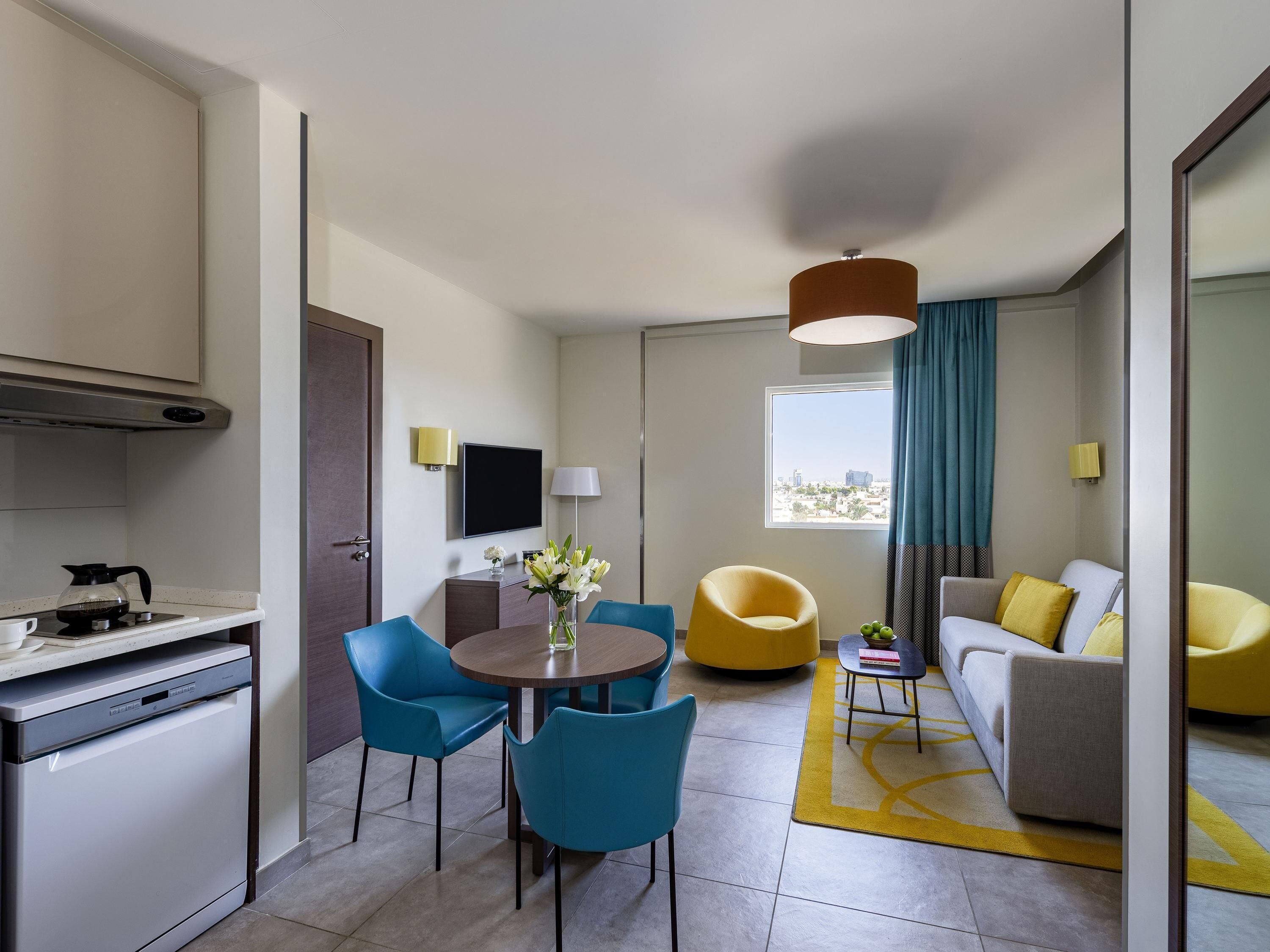 A modern hotel room with a kitchen, dining area, and living space.