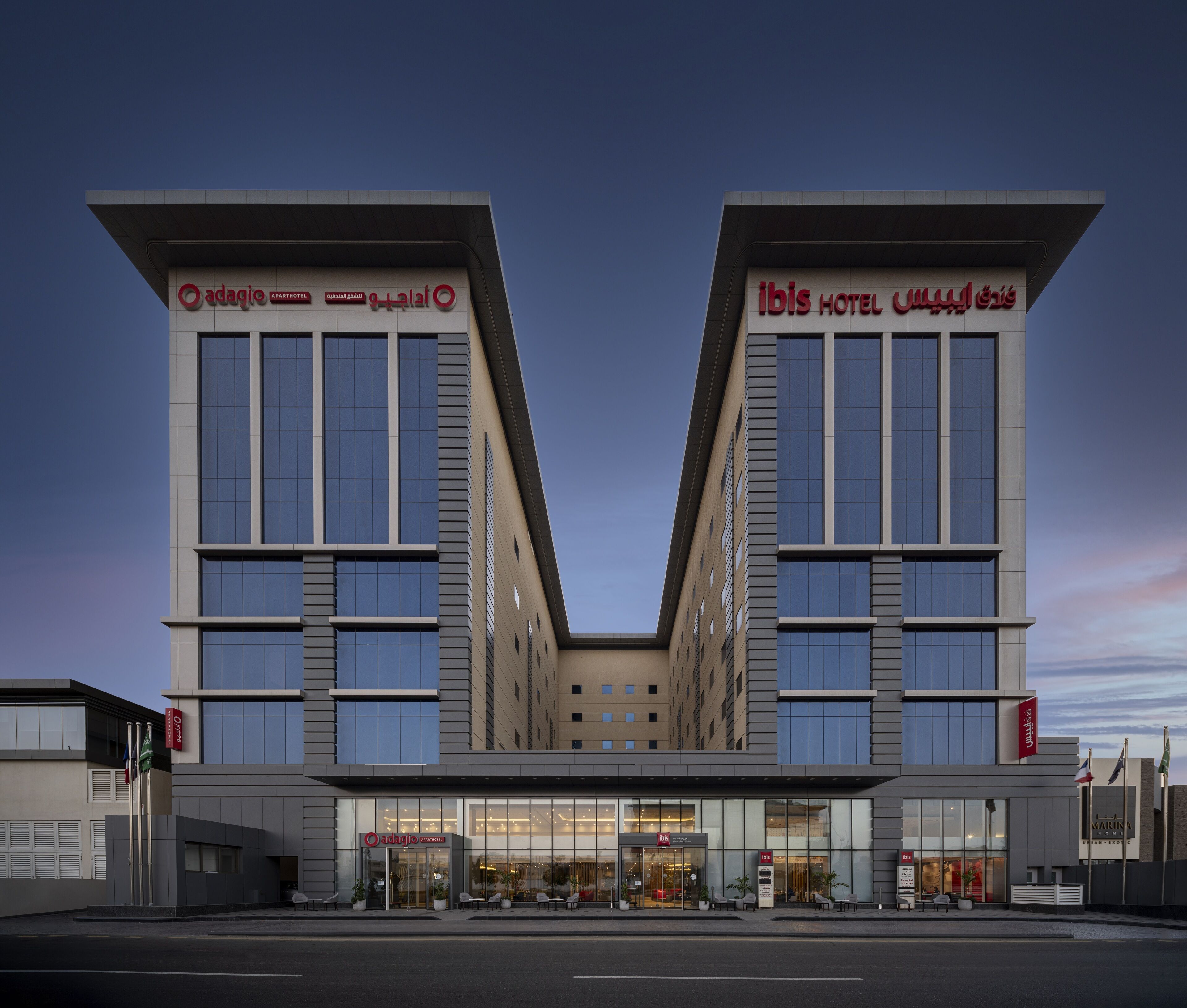 A modern hotel with a symmetrical facade, large windows, and a central entrance.