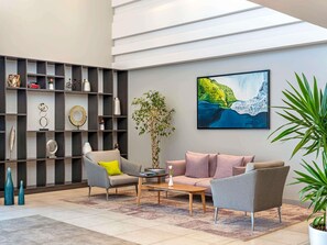 A modern living room with a sofa, armchairs, a coffee table, and a bookshelf.