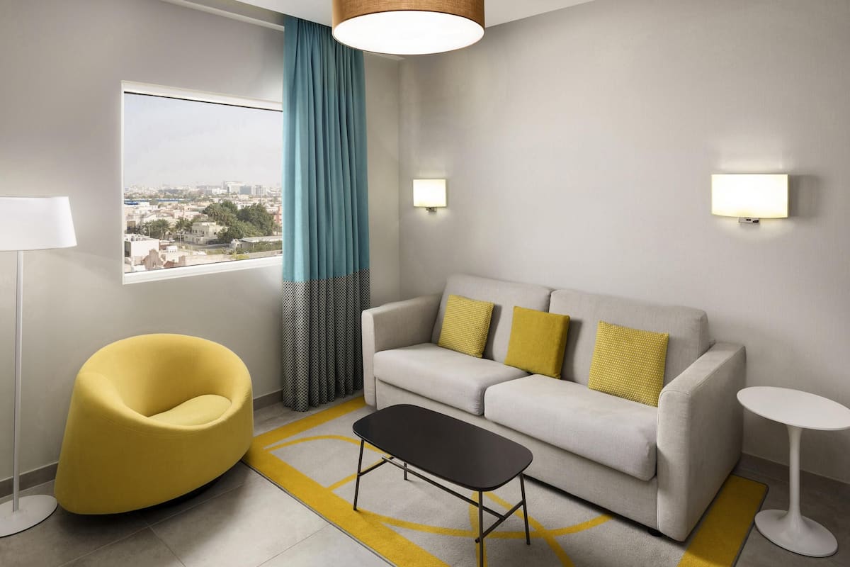 Een moderne woonkamer met een bank, een gele fauteuil en een kleine tafel.