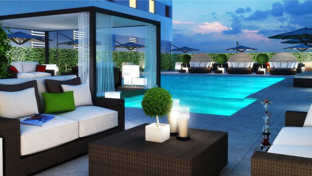 Un espace piscine extérieur moderne, doté de chaises longues, d’un canapé et d’un coin bar agrémenté de bougies et d’un narguilé.