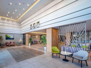 Eine geräumige Lobby mit hoher Decke, moderner Beleuchtung und Sitzbereichen.
