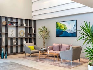 Een moderne woonkamer met een bank, fauteuils, een salontafel en een boekenkast.