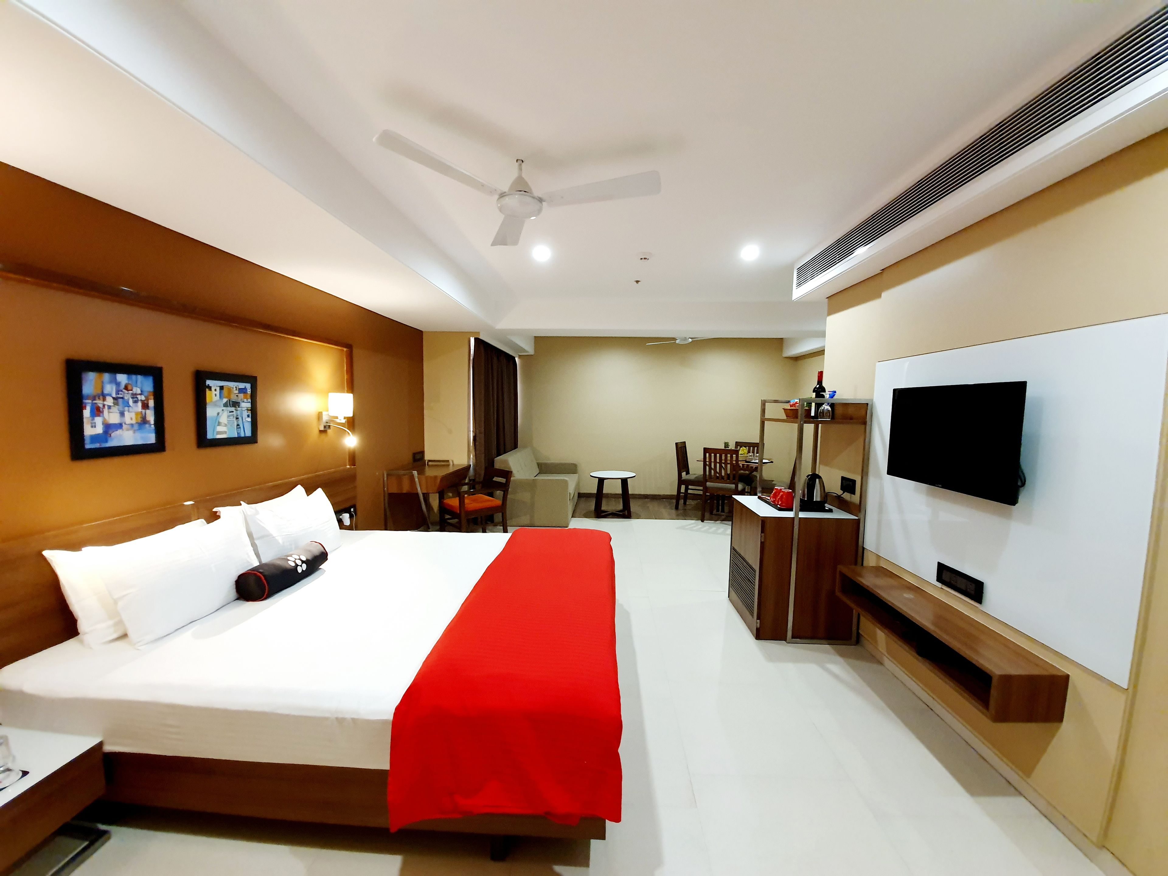 A hotel room with a bed, a TV, a desk, and a seating area.