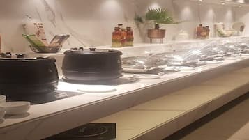 A long, well-lit display of various kitchenware and utensils, including pots, pans, and bowls, arranged on a marble countertop.