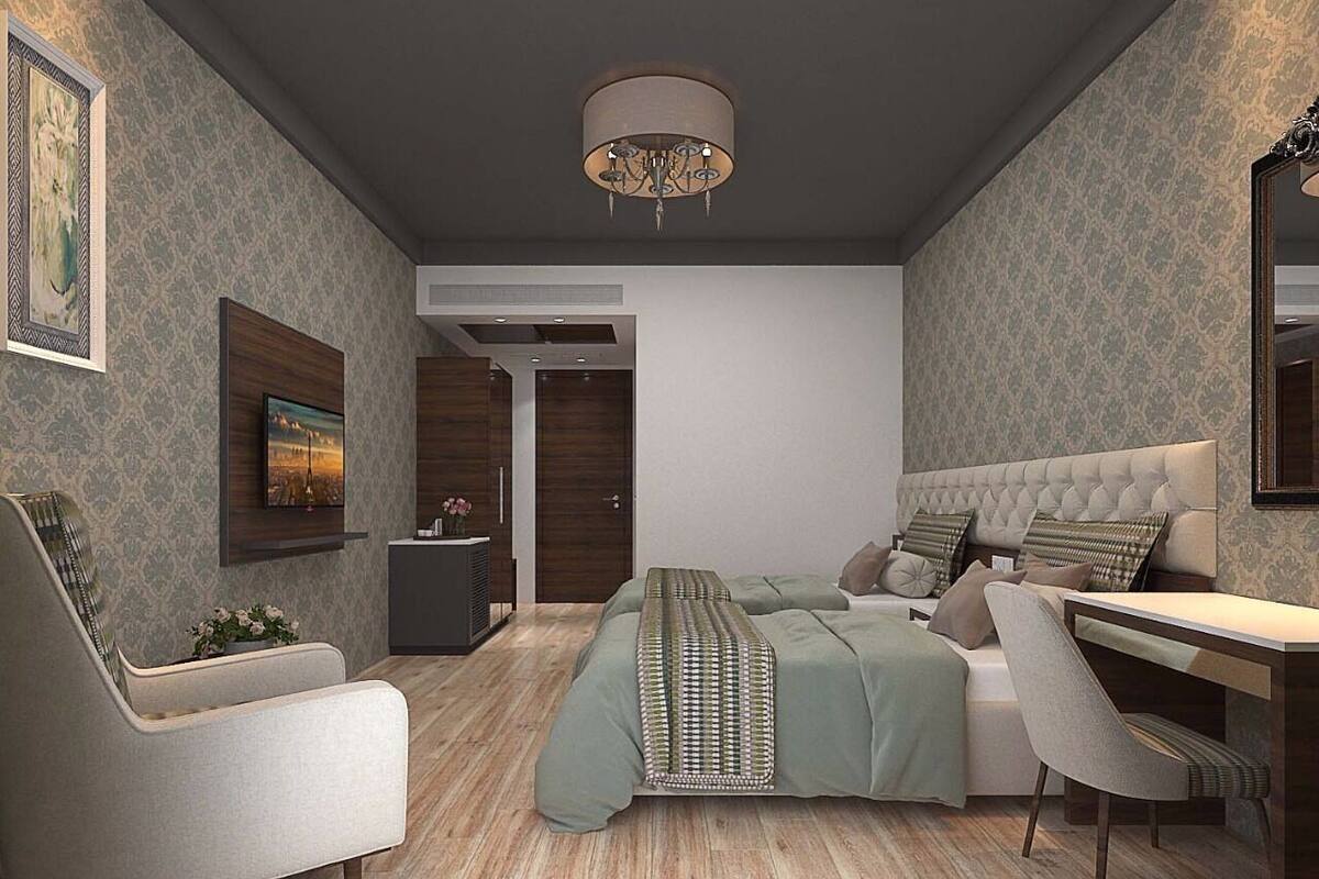 Un dormitorio moderno con una cama grande, un escritorio y una silla. Hay un televisor en la pared y una puerta que da a otra habitación.