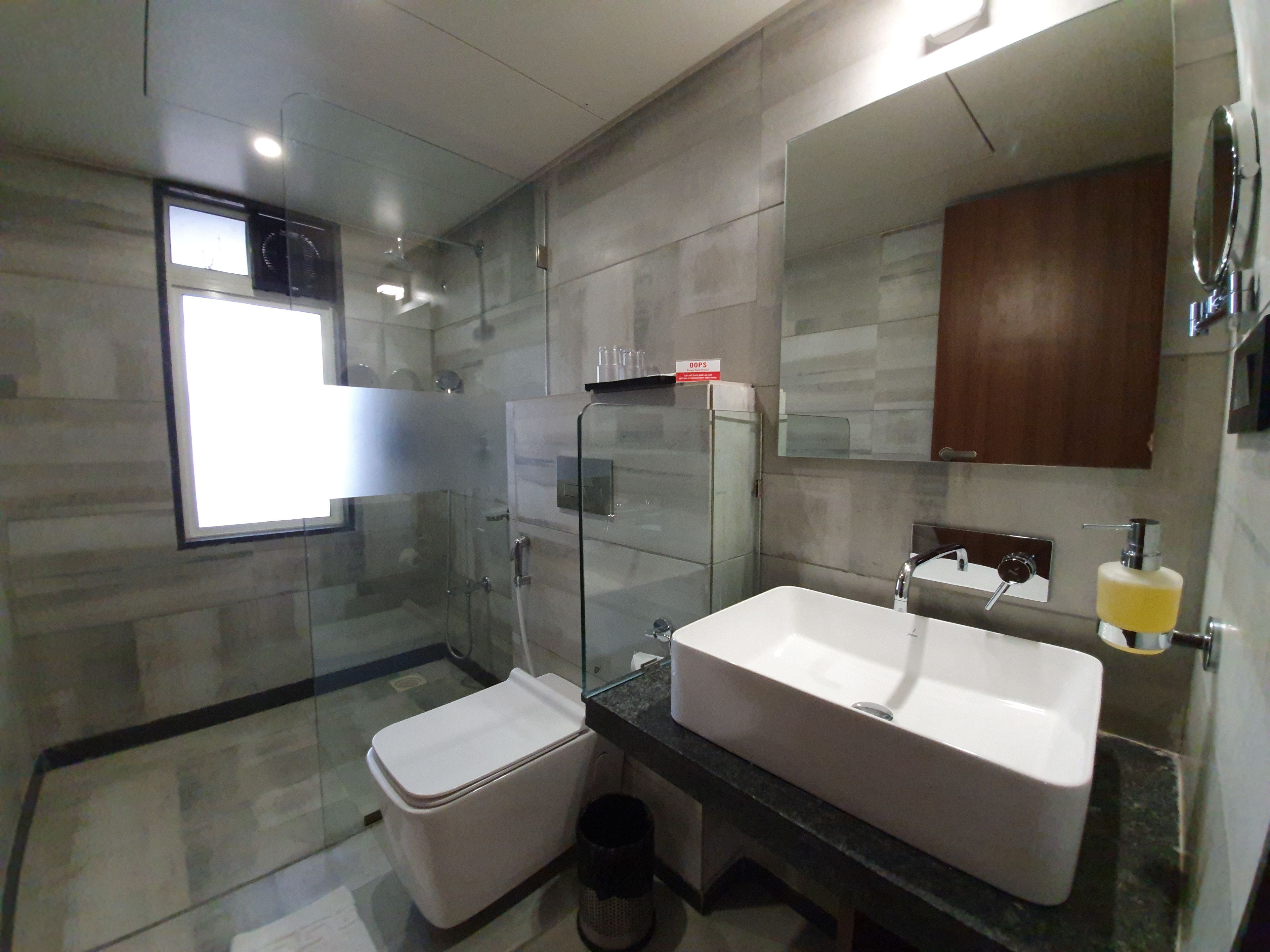 A modern bathroom with a glass-enclosed shower, a white sink, and a mirror above it.