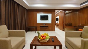 Una sala de estar moderna con dos sofás, una mesa de centro con una cesta de frutas, un televisor y paneles de madera.