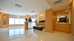 A spacious lobby with a reception desk, a sofa, and a coffee table. - Harbour Suites Hotel from Holiday Gulf Hotel (Manama)