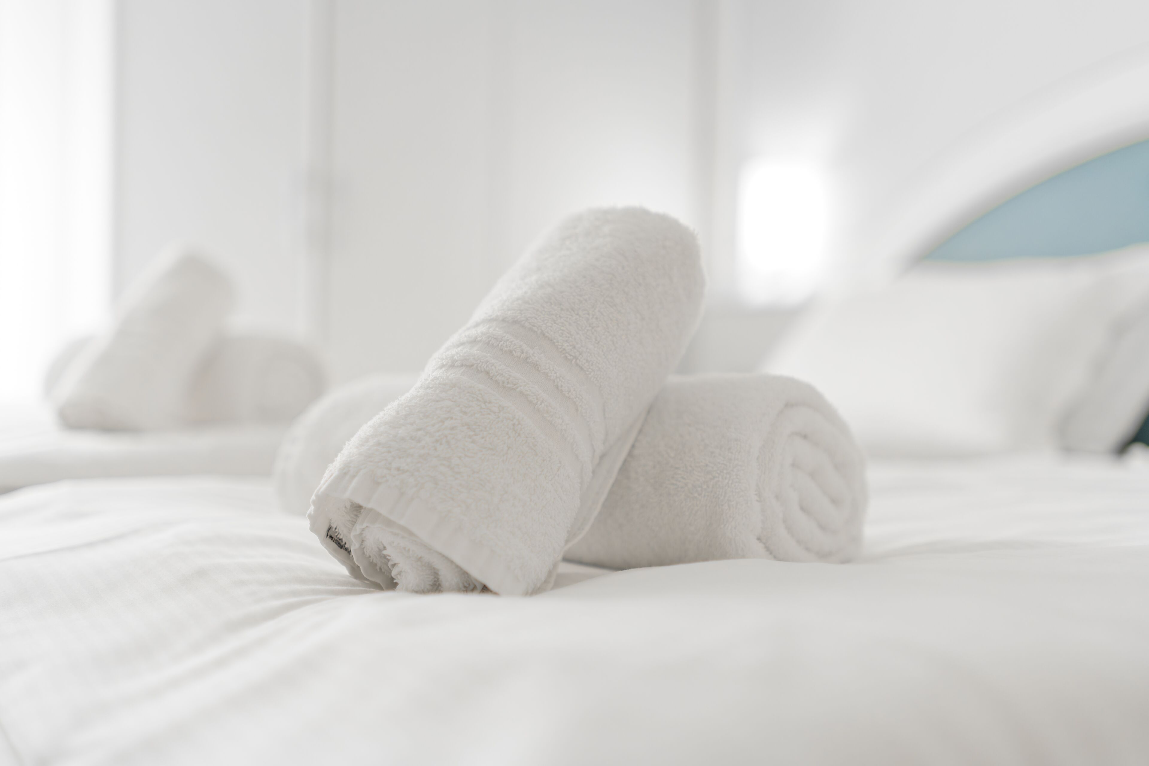 A neatly made bed with rolled white towels.