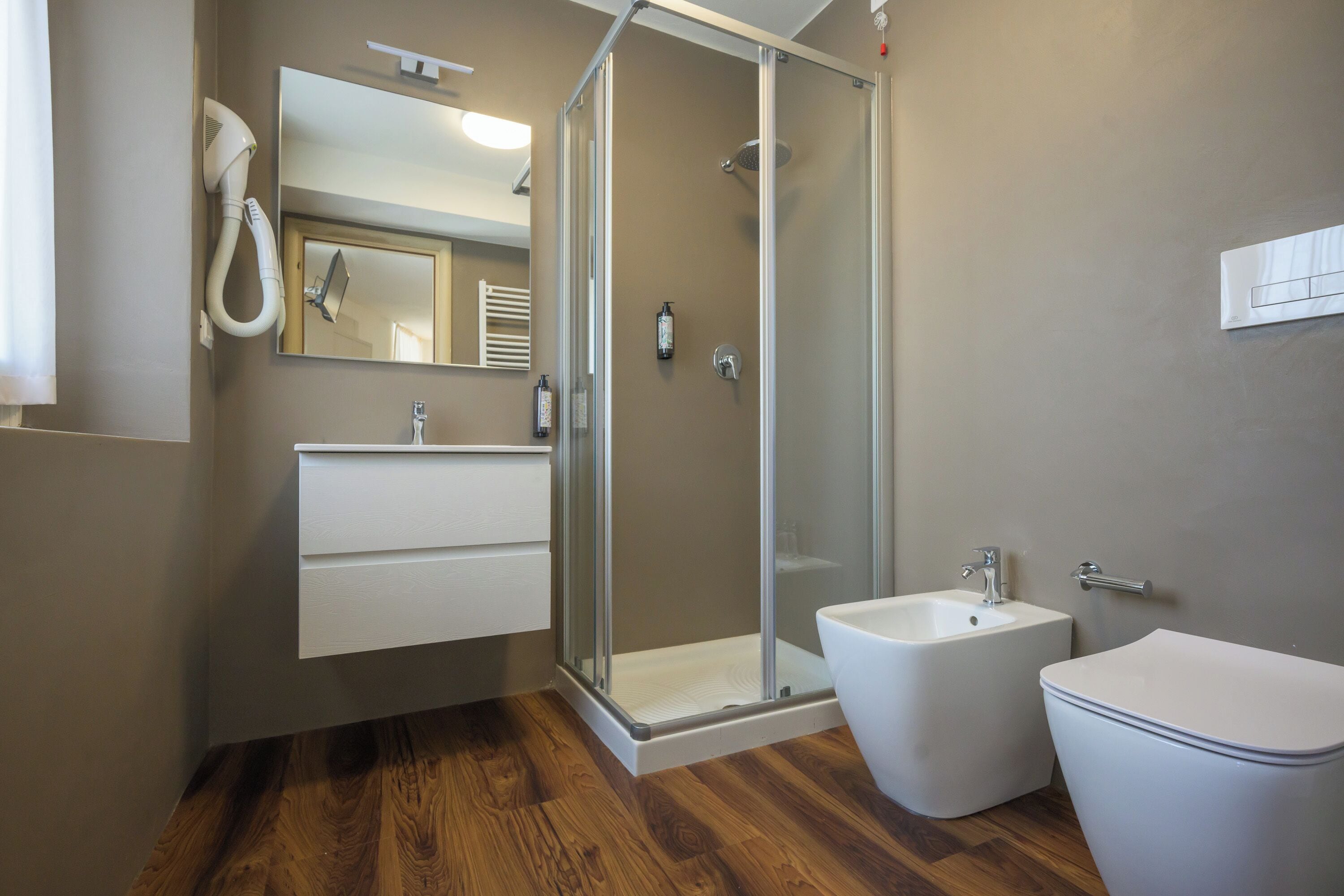 A modern bathroom with a glass-enclosed shower, a white sink, and a toilet.