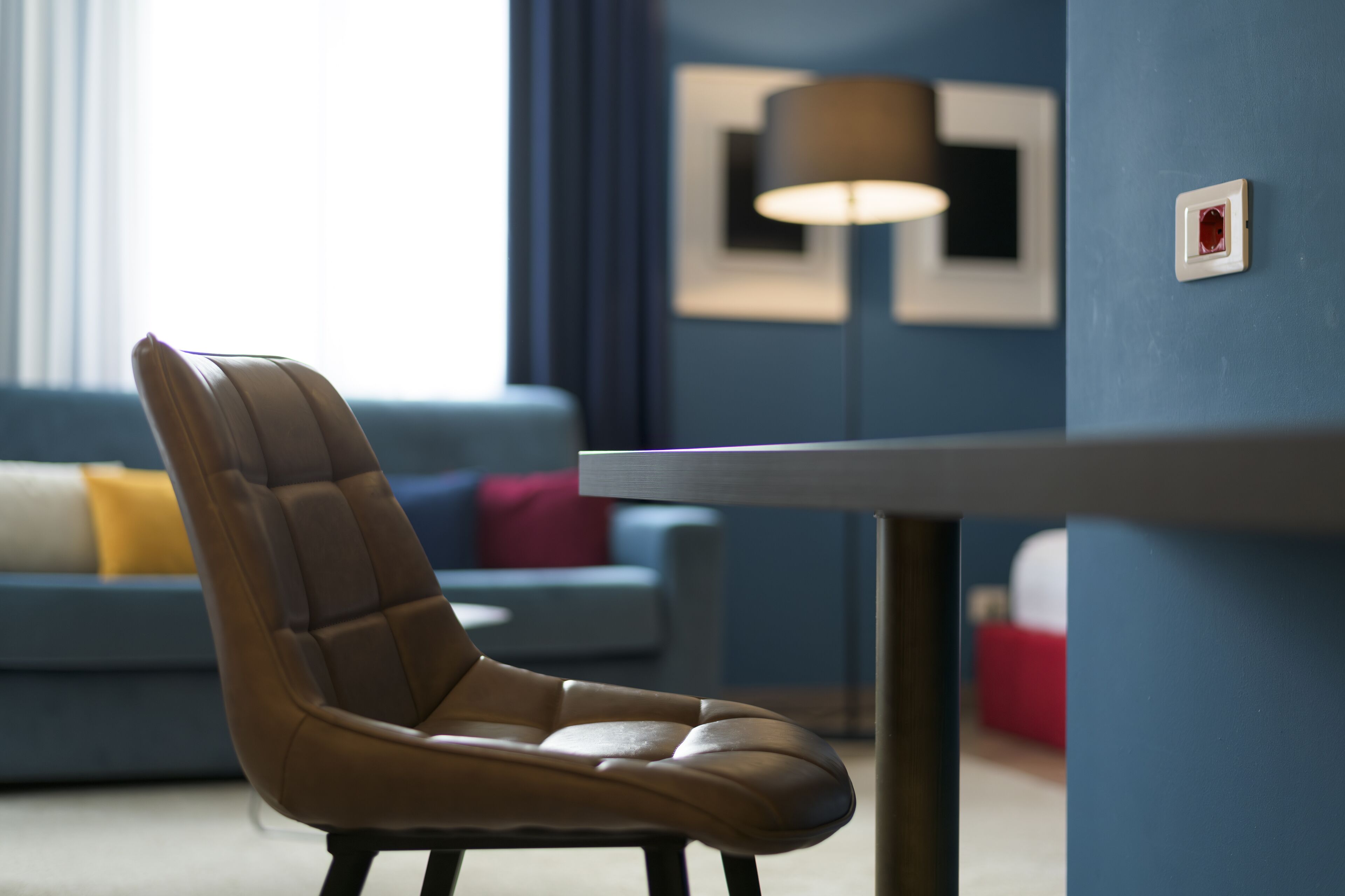 A modern living room with a leather chair, a blue sofa, and a table.