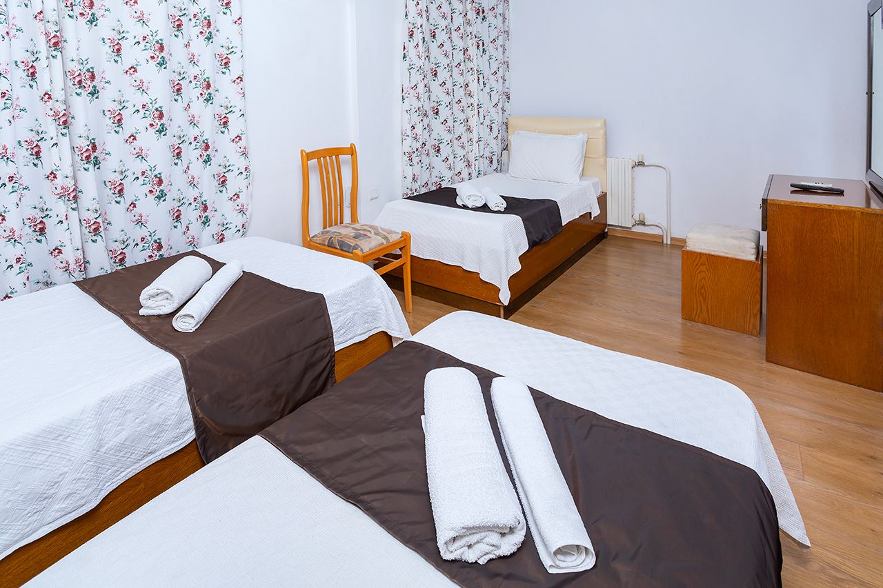 A hotel room with two beds, a chair, a desk, and a television.
