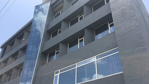 Un edificio de varios pisos con un diseño arquitectónico moderno, que combina fachadas de vidrio y concreto.