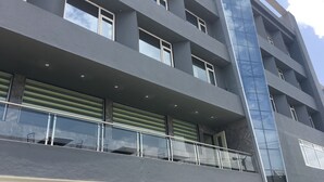 Un edificio de varios pisos con un diseño arquitectónico moderno, que cuenta con balcones con barandillas de vidrio y ventanas amplias.