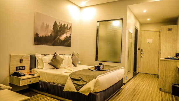 Una habitación de hotel con cama, mesita de noche y un cuadro en la pared.