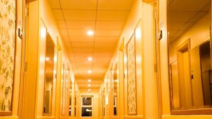 Un pasillo de hotel con suelo alfombrado, puertas a ambos lados y techo con iluminación empotrada.