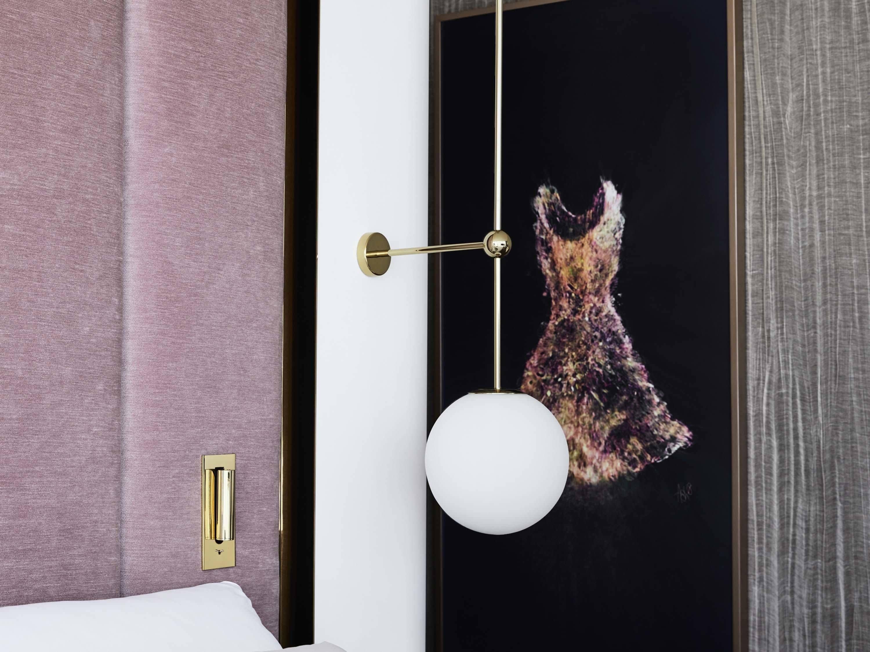 A room with a bed, a wall-mounted light fixture, and a door with a framed artwork.