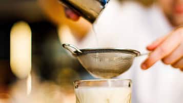 A person pouring milk into a glass using a strainer.