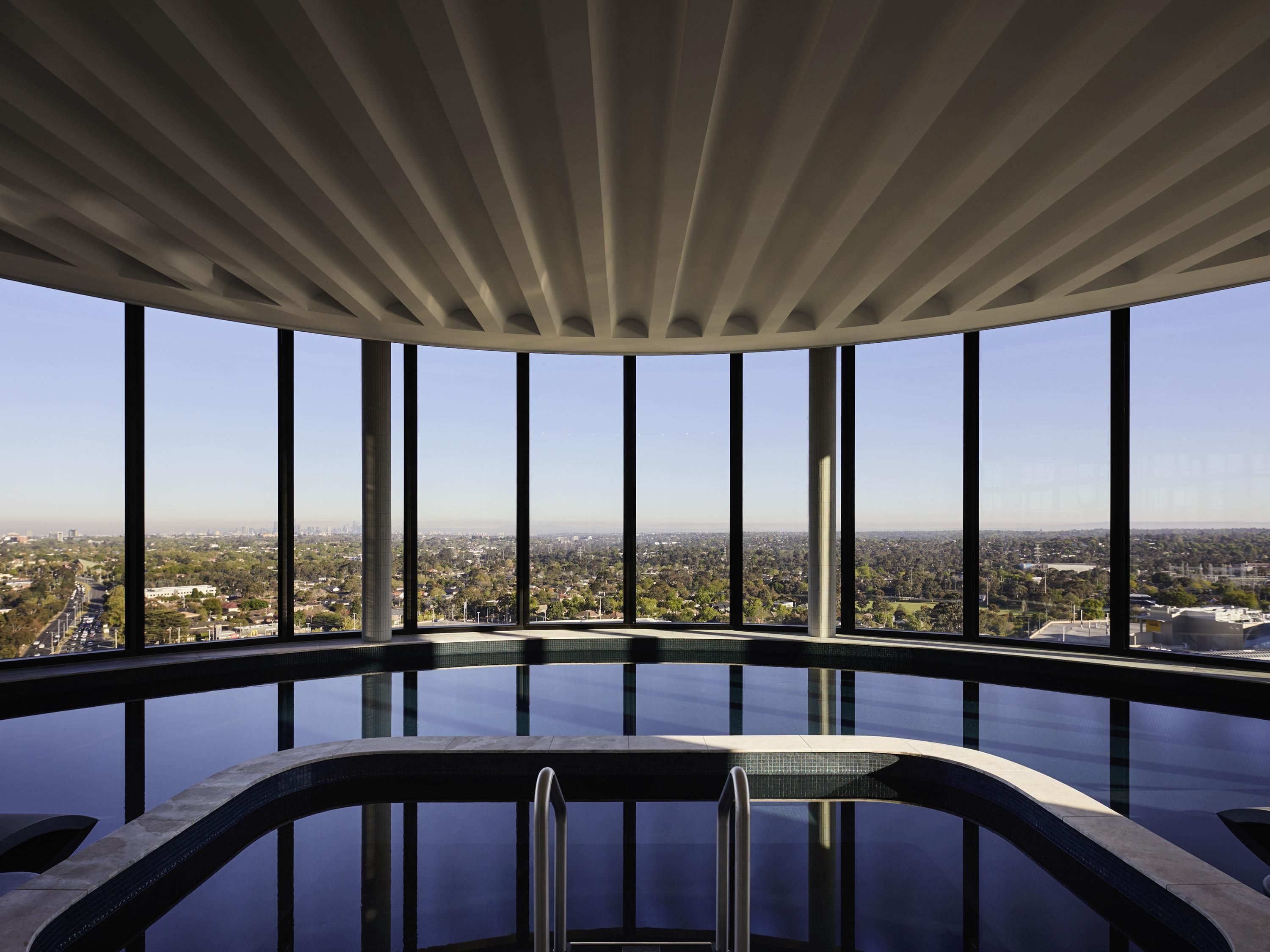 A modern infinity pool with a clear view of the cityscape through large windows.