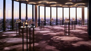 A modern interior with large windows, multiple tables with candles, and a city view. - Hotel Chadstone Melbourne MGallery Collection (Chadstone)