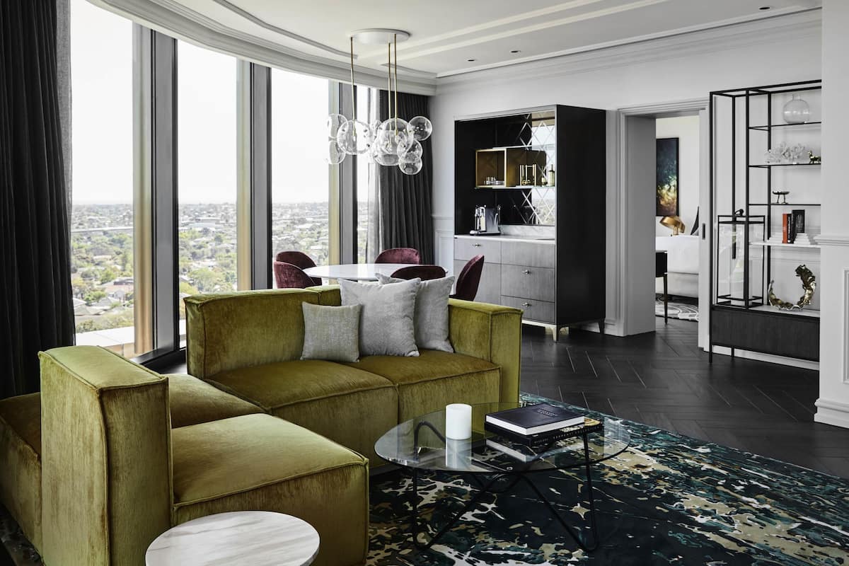 A modern living room with a green sofa, a round coffee table, and a view of the city through large windows.