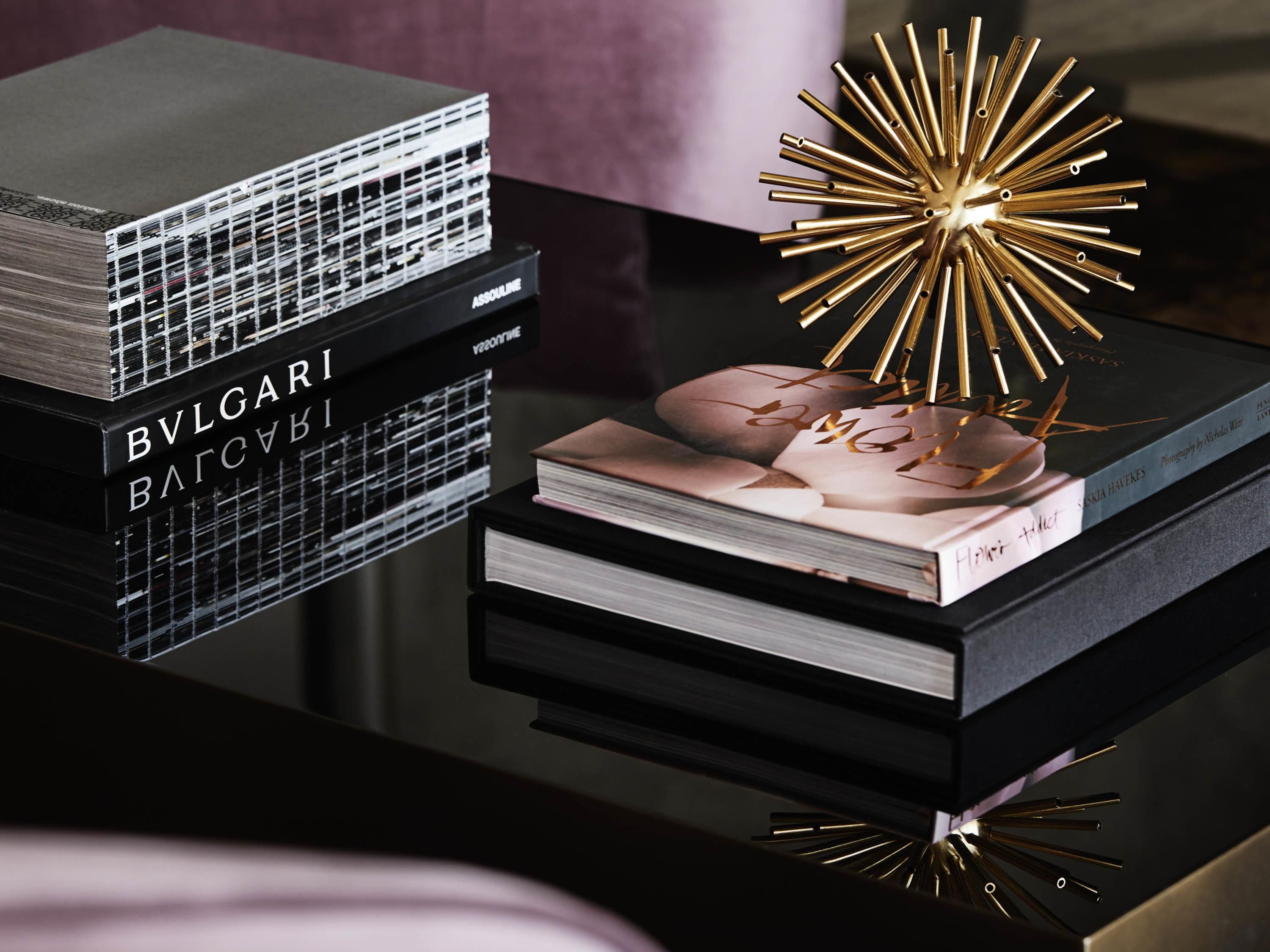 Een stapel boeken met 'BVLGARI'-branding, een decoratieve gouden ster en een boek getiteld 'Horizon'.