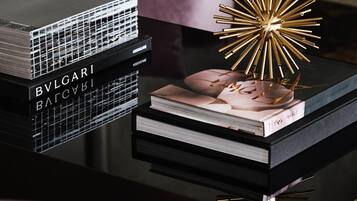 A stack of books with 'BVLGARI' branding, a decorative gold star, and a book titled 'Horizon'.