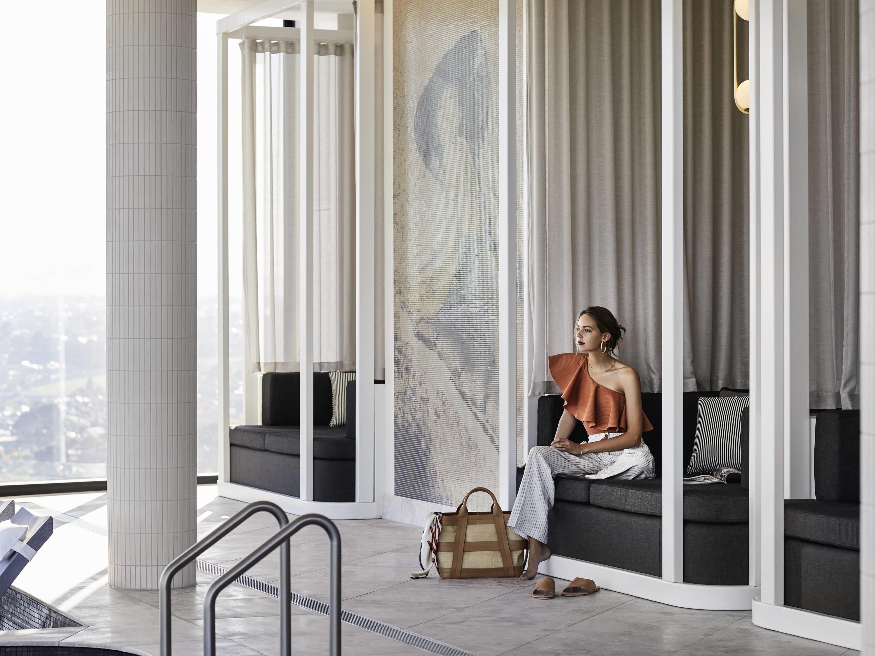 A modern interior with a large window, a seating area with a sofa and cushions, and a patterned wall.