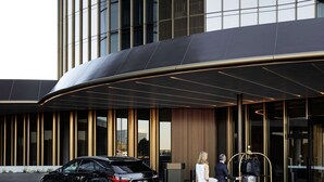 Un edificio moderno con un toldo curvo de entrada y listones verticales de madera.