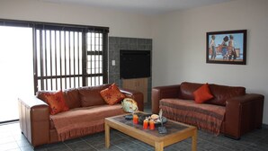 A living room with two brown leather sofas, a coffee table, and a painting on the wall. - On The Dunes 8 (Henties Bay)