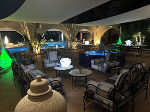 Un espace extérieur aménagé avec une terrasse, des sièges, une piscine et un éclairage d’ambiance.