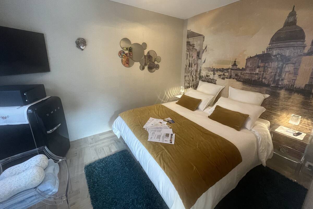 Ein Hotelzimmer mit einem Bett, einem Flachbildfernseher, einem wandmontierten Spiegel und einem Stadtbild-Mural.