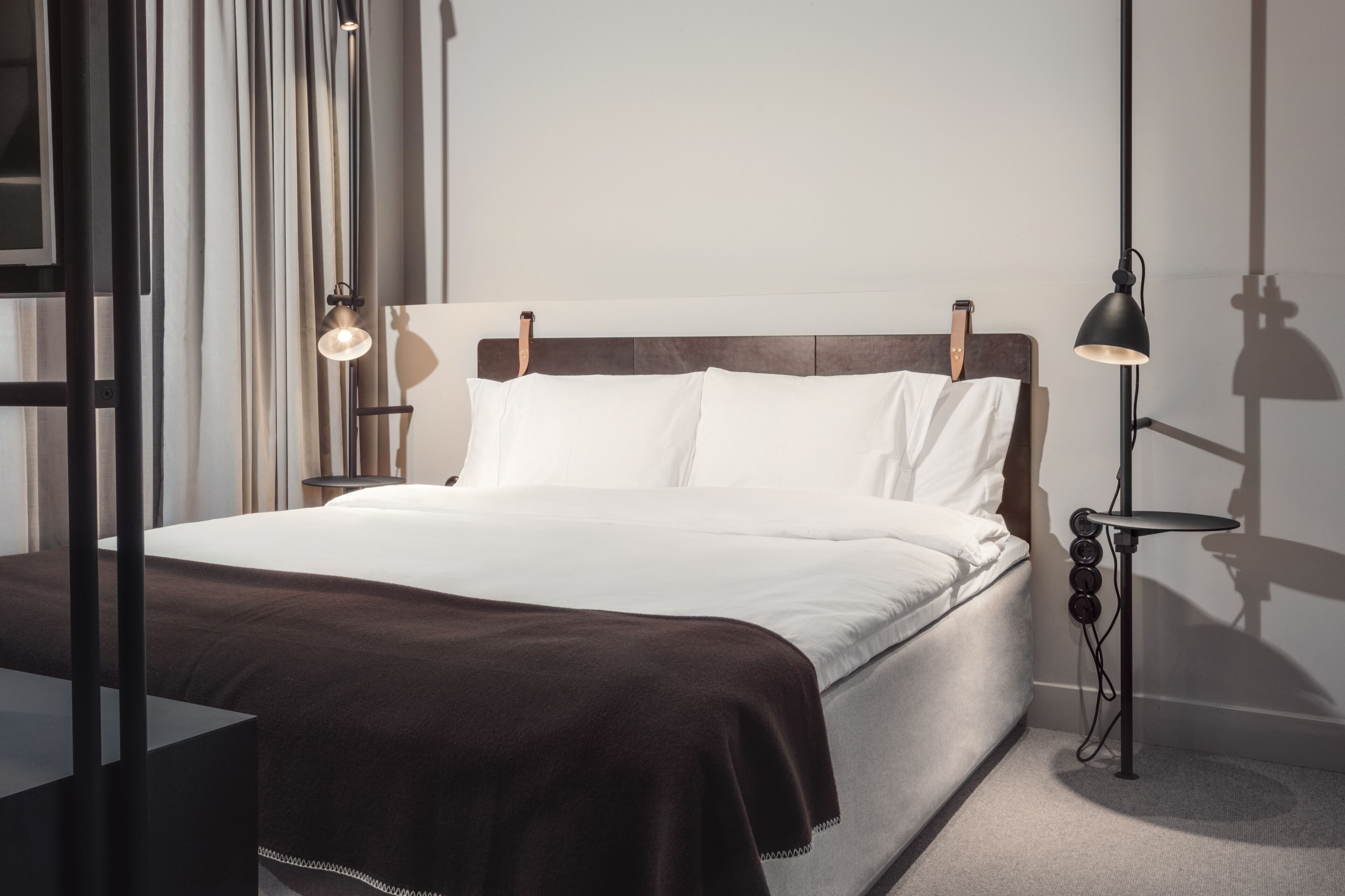 A modern bedroom with a large bed, a bedside table, and a floor lamp.