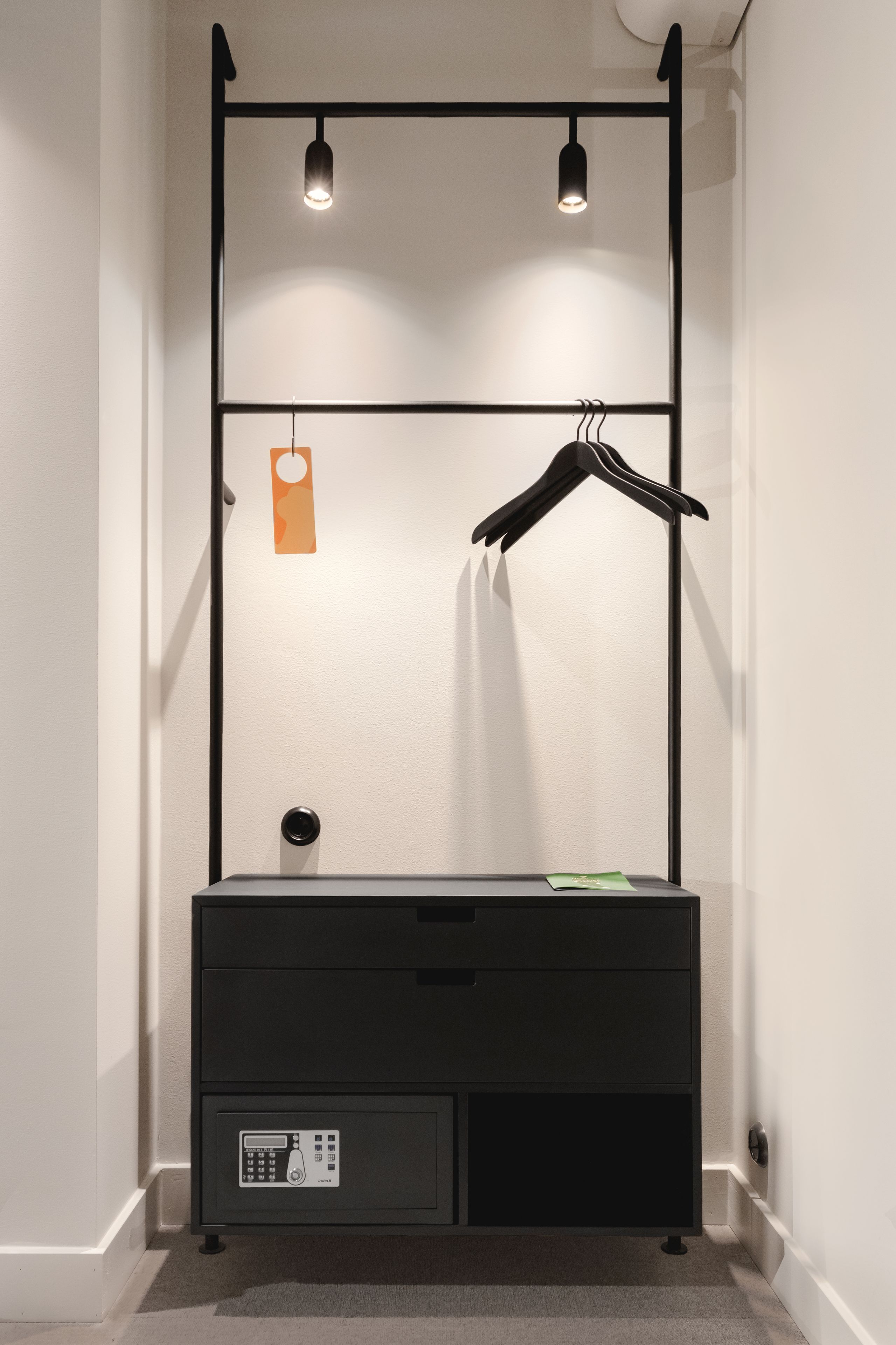 Un baño moderno y minimalista con un mueble de tocador negro, un perchero para toallas y un pequeño armario.