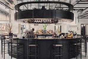 A modern bar area with a central circular bar, multiple stools, and a variety of bottles and glasses. - Blique by Nobis, Stockholm, a Member of Design Hotel (Stockholm)
