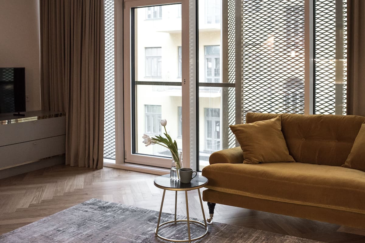Ein modernes Wohnzimmer mit einer Couch, einem kleinen runden Tisch mit Blumenvase und einem Fernseher auf einem Schrank.