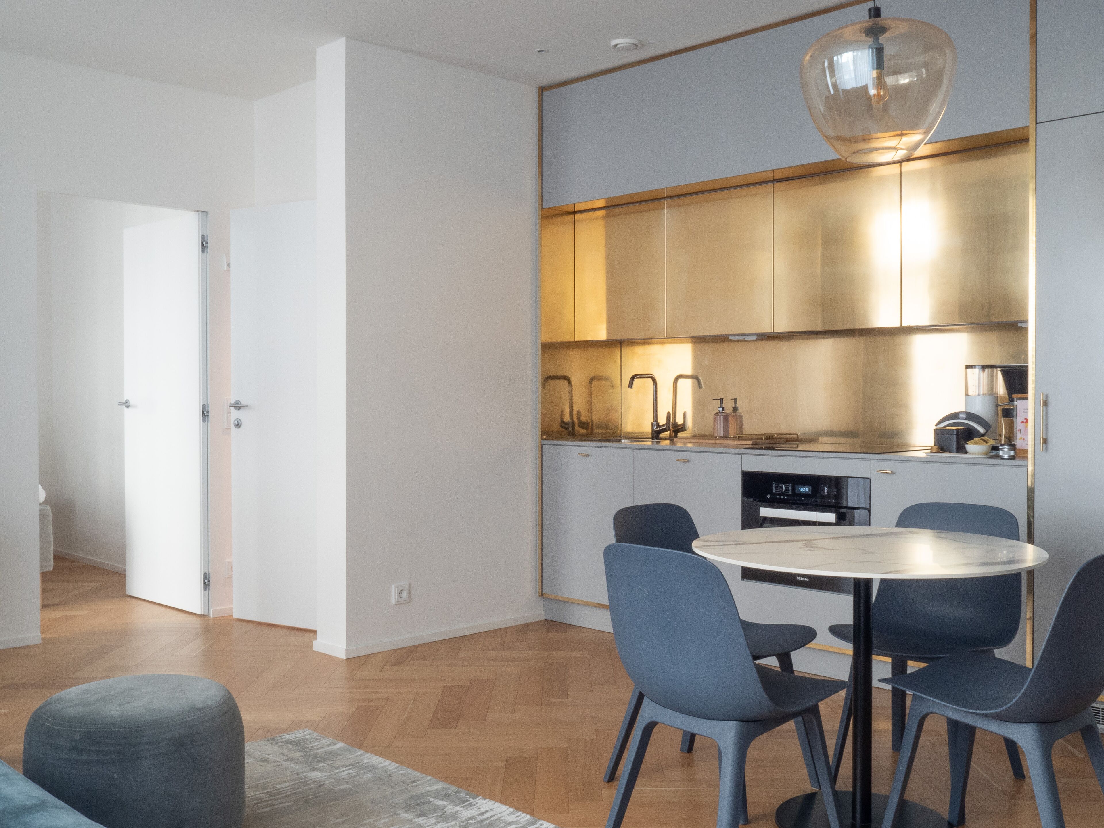 Una cocina moderna con una mesa redonda de comedor y cuatro sillas, una cafetera y un lavavajillas.