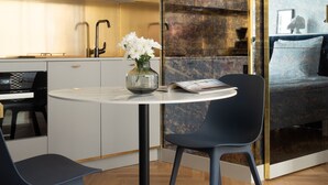 A modern kitchen with a white countertop, black chairs, and a round table. - Bob W Helsinki Ullanlinna (Helsinki)