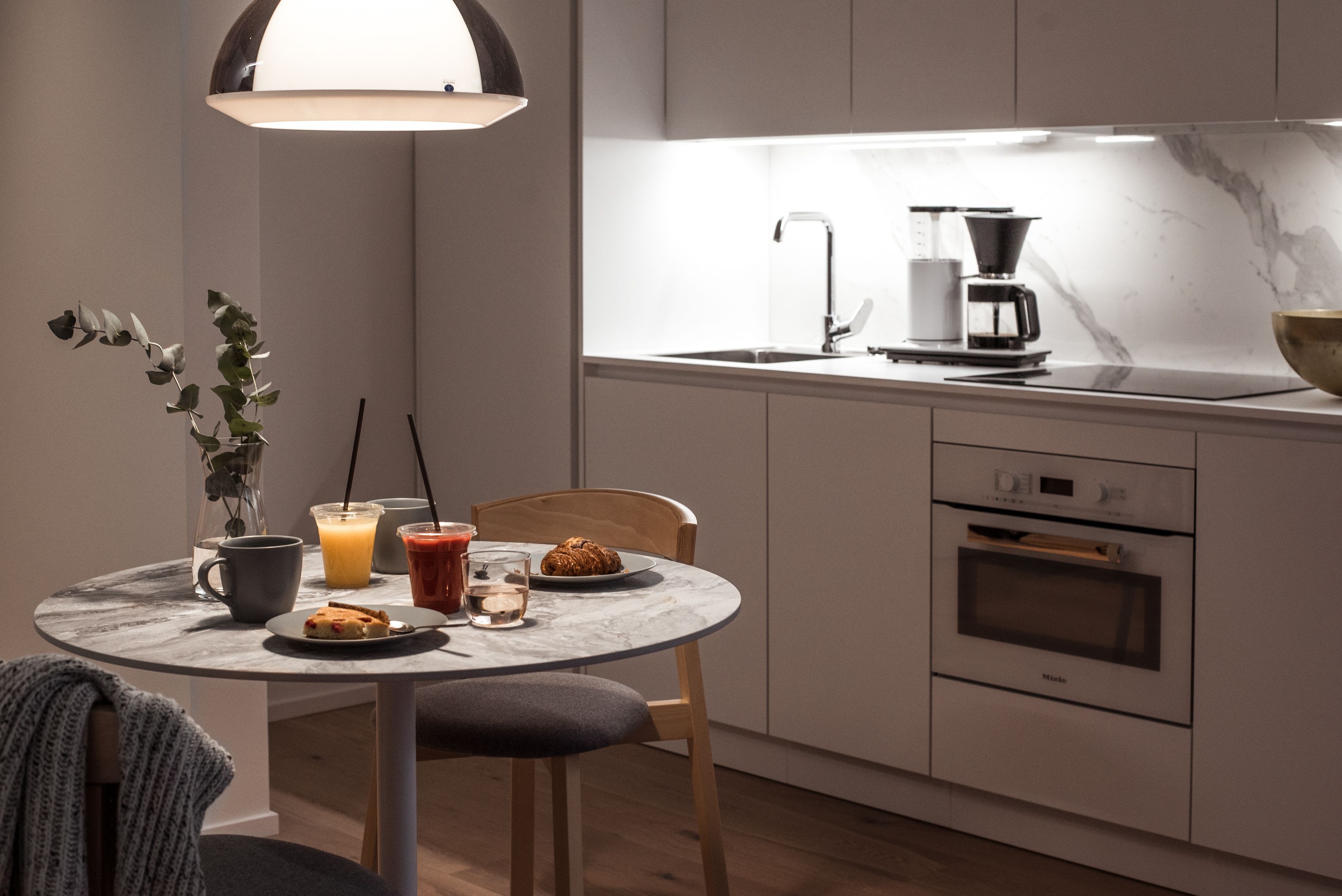 A modern kitchen with a round dining table, a coffee maker, and a microwave.