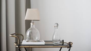 A clear glass lamp and a vase on a metal table with a book.