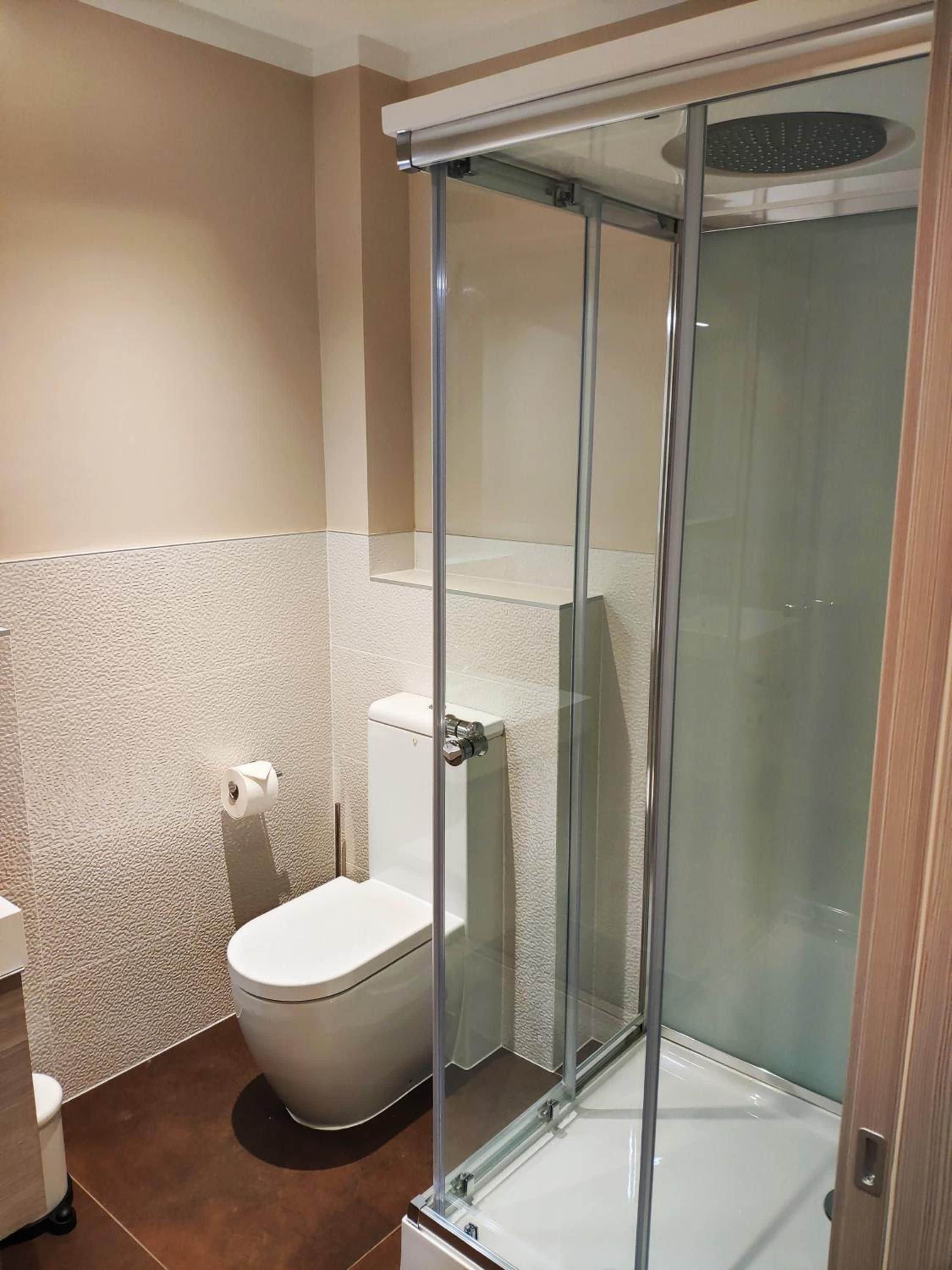 A bathroom with a glass-enclosed shower, a toilet, and a towel rack.