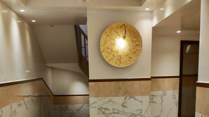 Un hall d’entrée moderne avec des murs en marbre, un sol à motifs géométriques et un éclairage encastré.