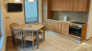 Une cuisine moderne avec des meubles en bois, un four encastré et un coin repas comprenant une table et des chaises.