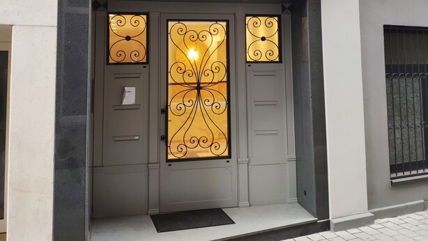 Une façade d’immeuble dotée d’une entrée moderne, avec une porte en verre et des éléments décoratifs en métal.