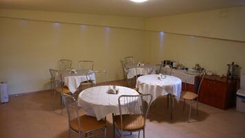 Un comedor con mesas redondas, sillas y una estación de café.