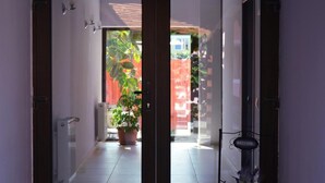 Un couloir avec une porte-fenêtre coulissante donnant sur un patio agrémenté d’un pot de fleurs et d’une pancarte de bienvenue.