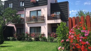 Un bâtiment à deux étages doté de balcons, un jardin fleuri et une clôture en bois.