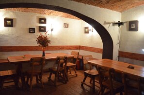 A rustic dining area with wooden tables and chairs, a brick ceiling, and framed pictures on the walls. - Pensiunea Andy (Brasov)